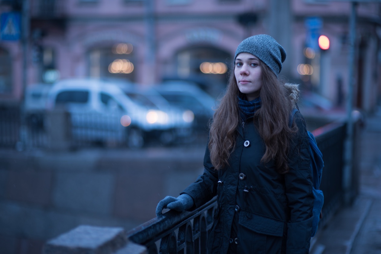 Young woman on a city embankment at dusk with an unnatural blue color cast