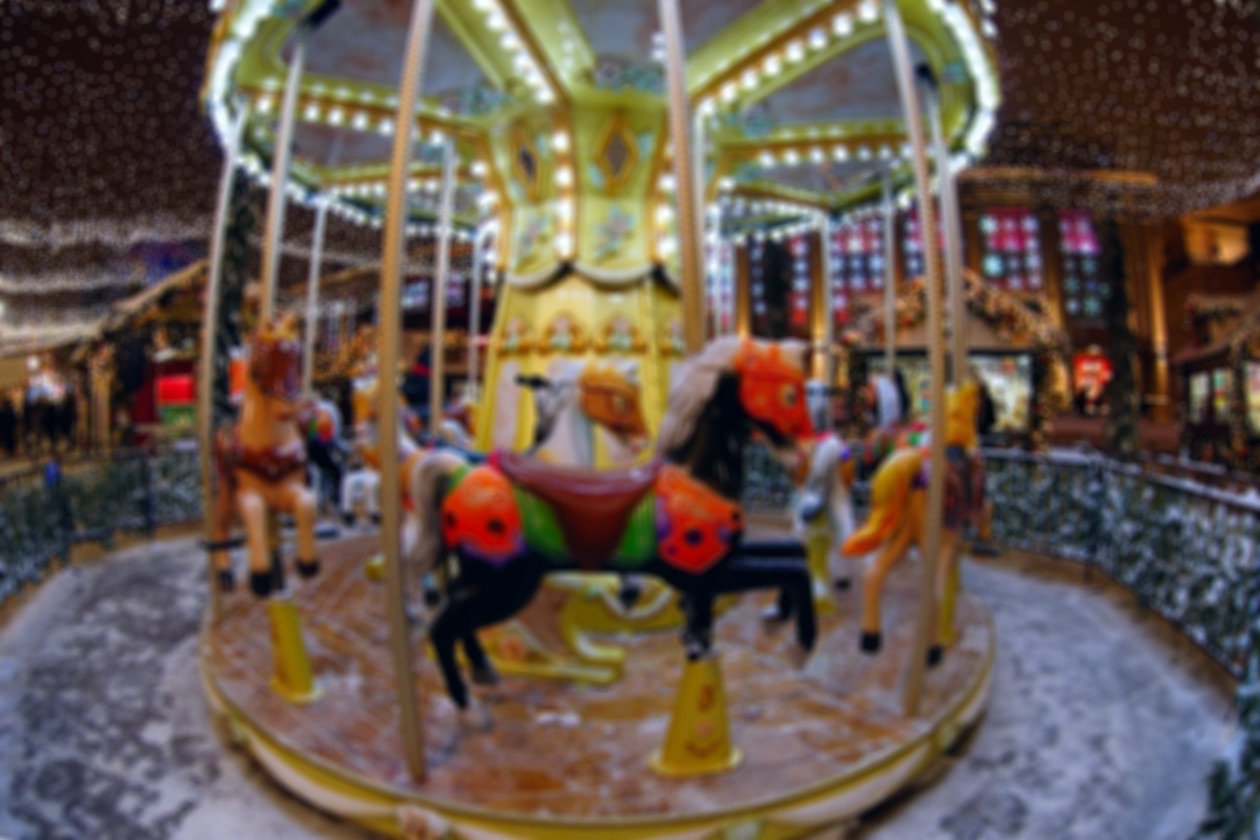 Lit-up carousel with horses photographed out of focus
