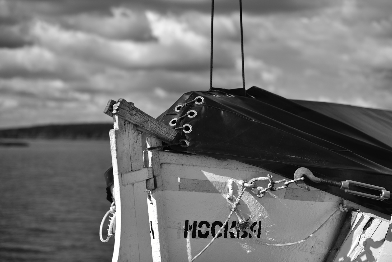 Black-and-white photo of a boat bow under a dramatic cloudy sky
