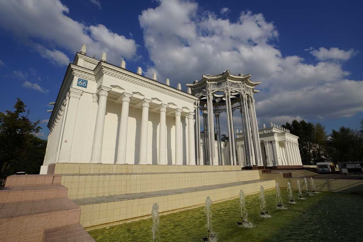 White colonnaded building with fountains under a deep blue sky with clouds