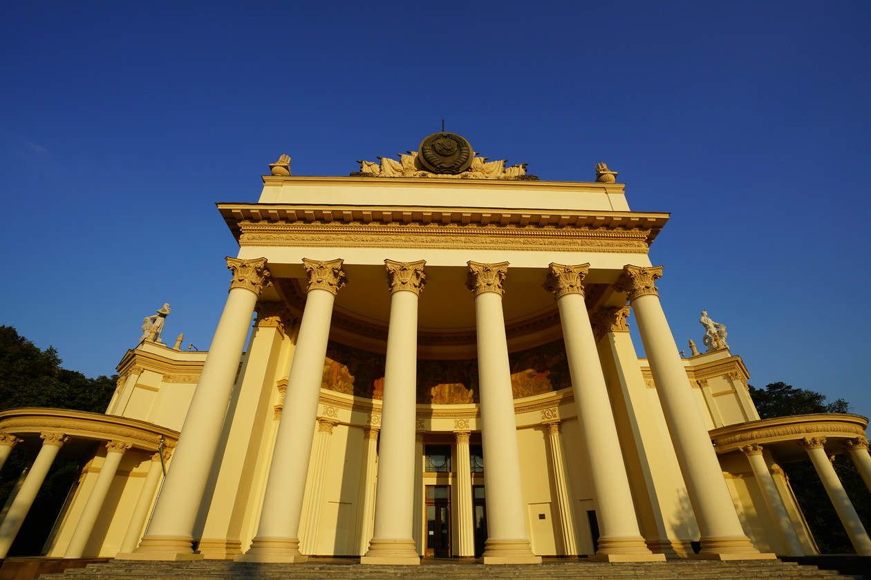 Low-angle view of a yellow colonnaded pavilion against a dark blue sky