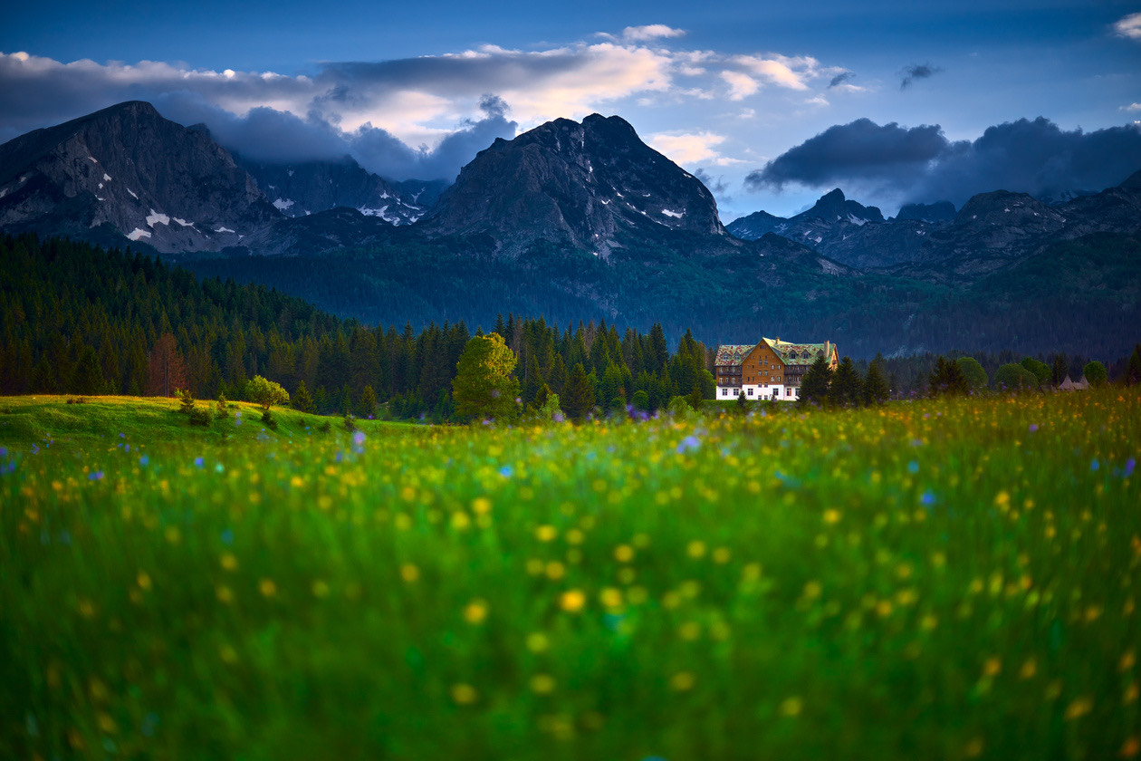Mountain meadow with a chalet below rugged peaks