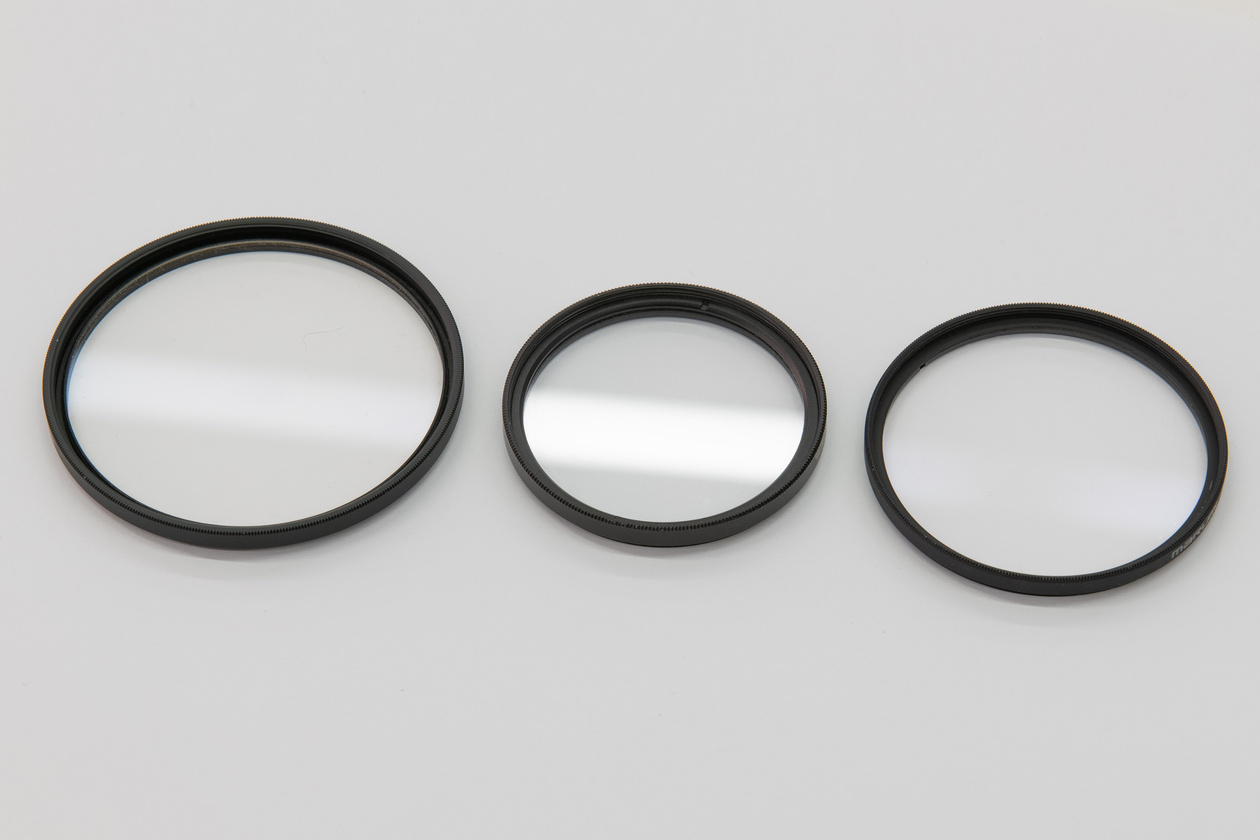 Three protective filters of different sizes on a gray background