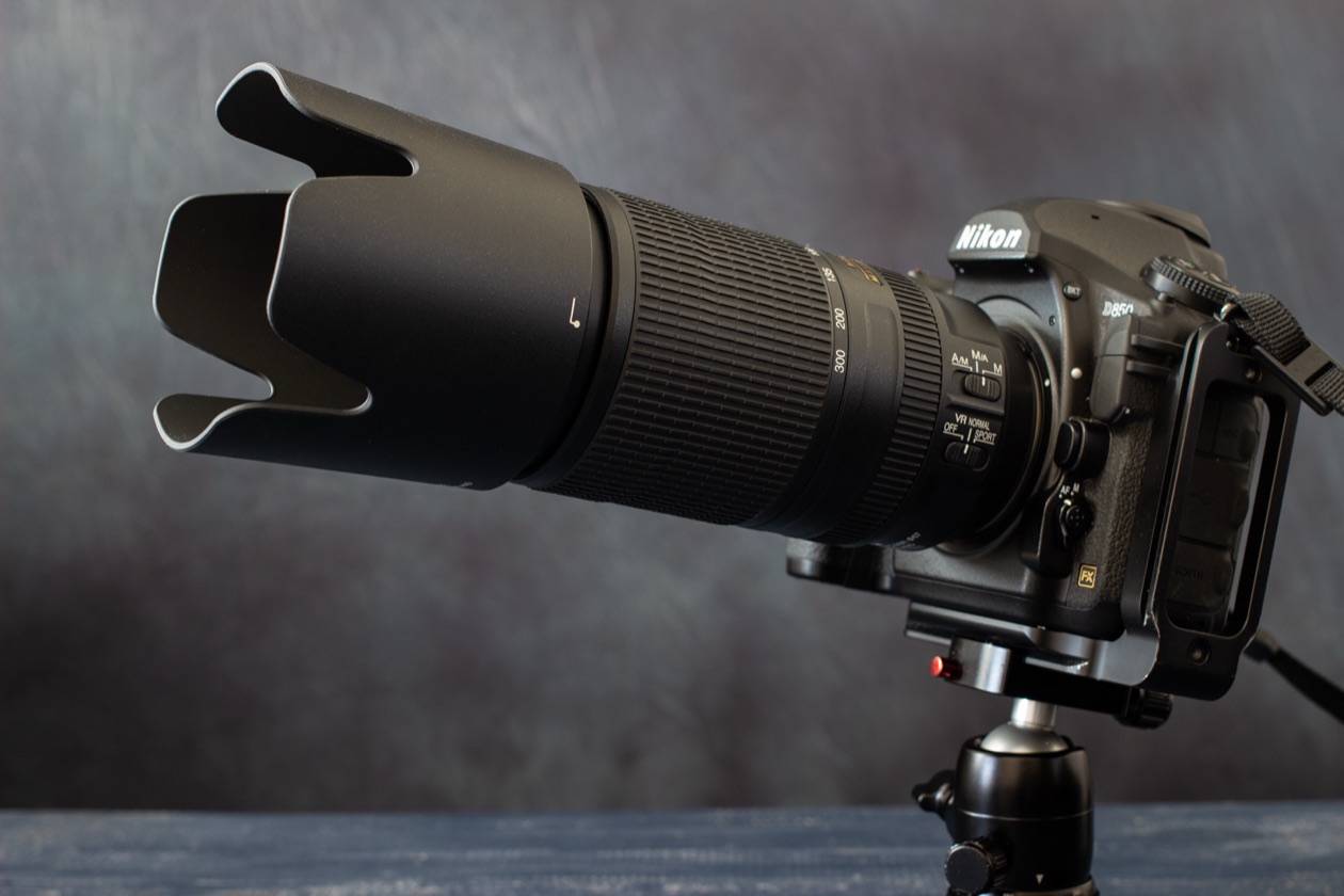 Nikon camera with a telephoto zoom lens and lens hood on a tripod