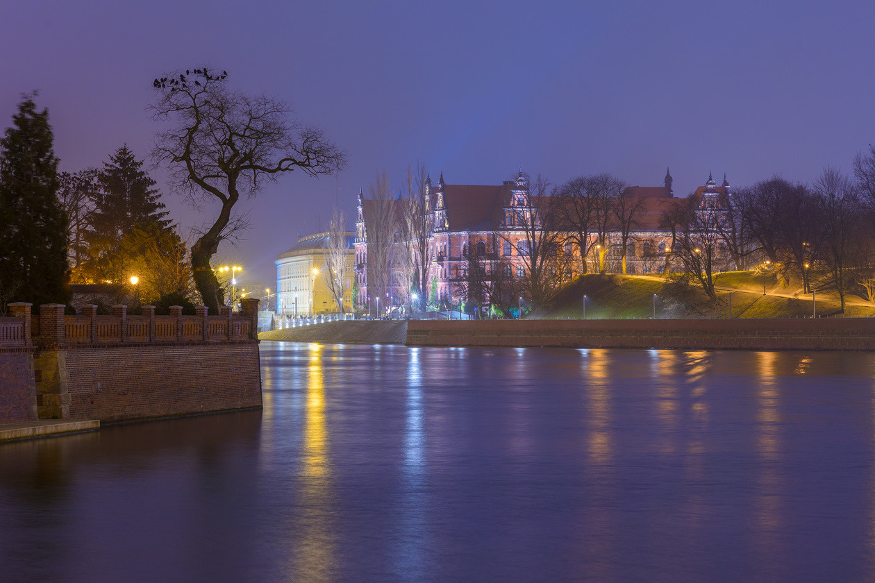 Illuminated riverside buildings reflected in the water at night