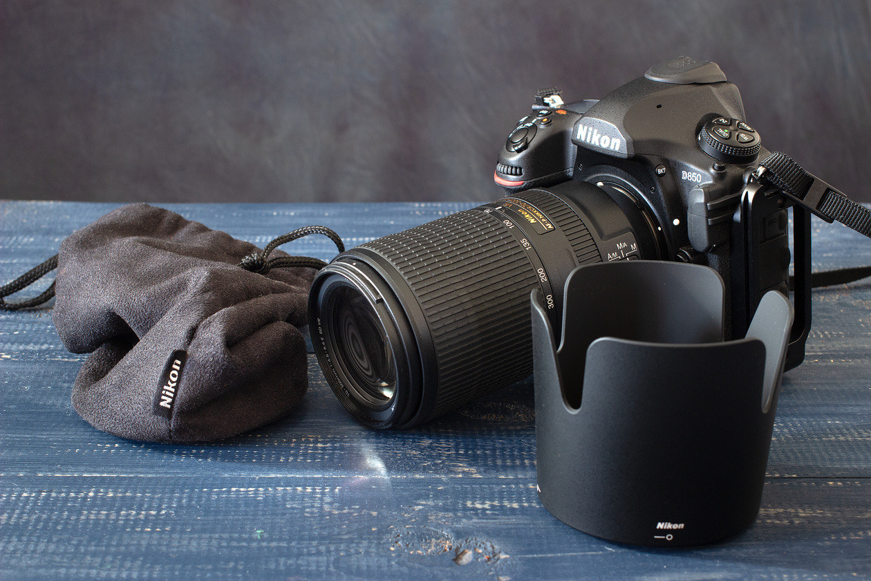 Nikon camera and lens next to a lens pouch and a lens hood