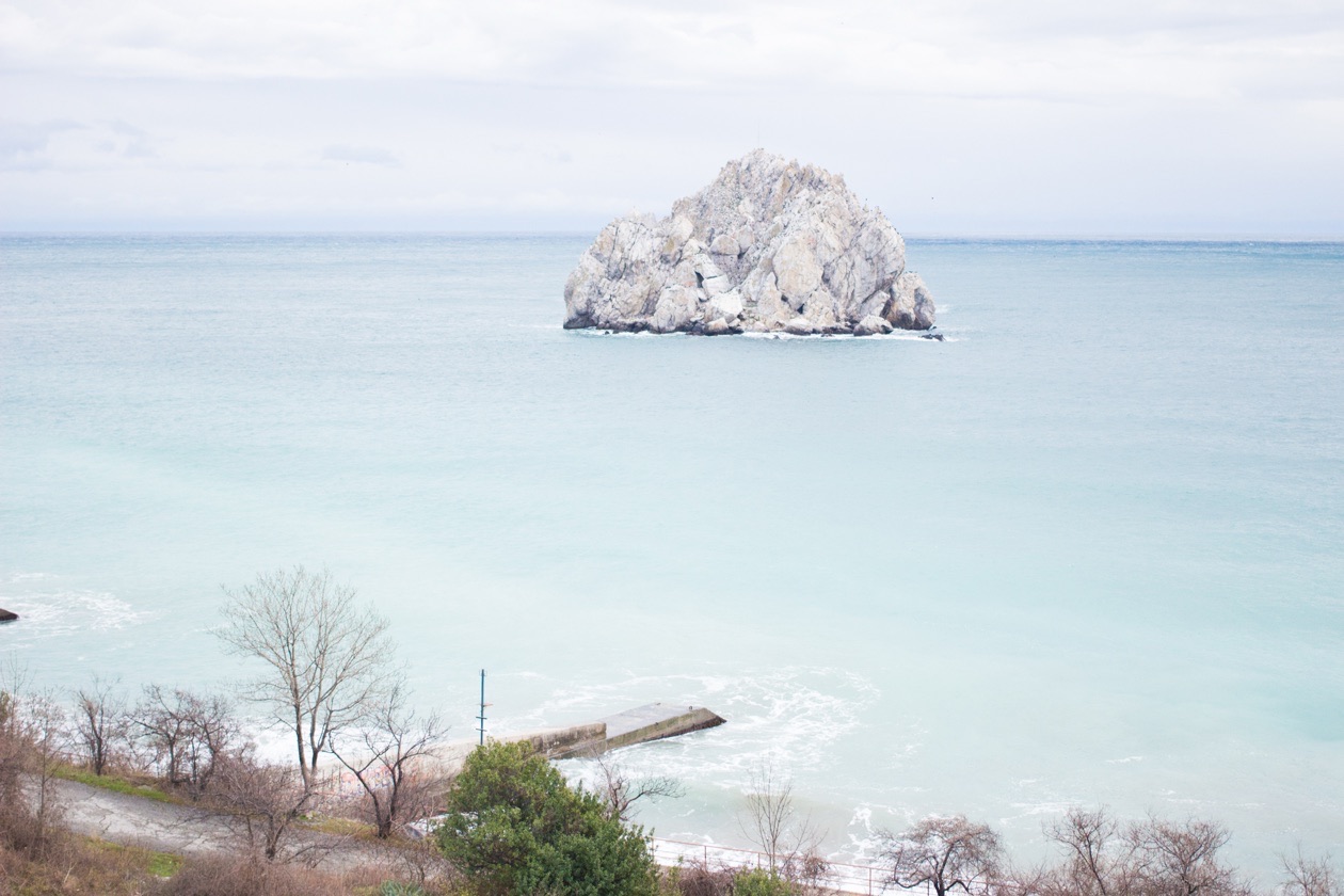 The same rock in the sea photographed far too bright, an overexposed frame