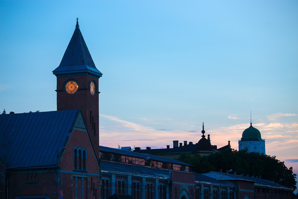 Red-brick clock tower with lit clock faces against a dusk sky