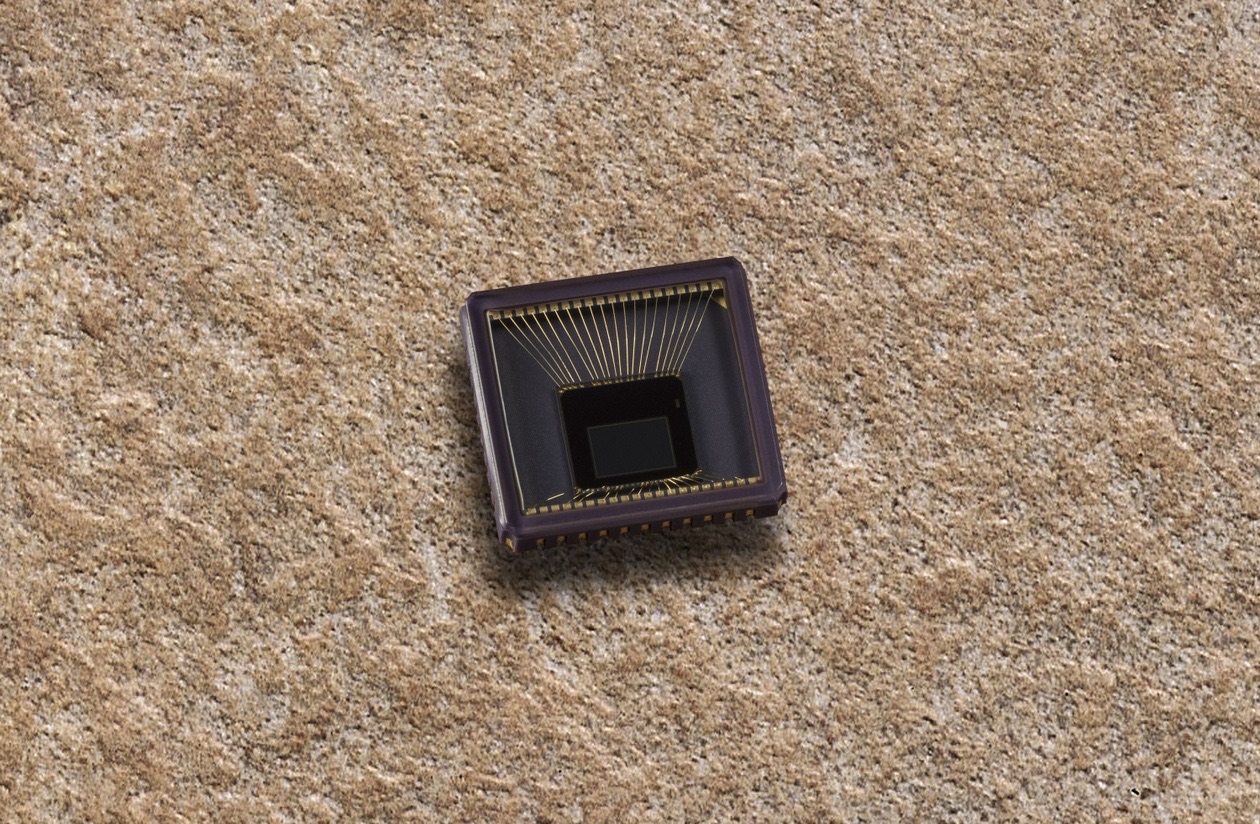 Bare image sensor chip lying on a textured stone surface