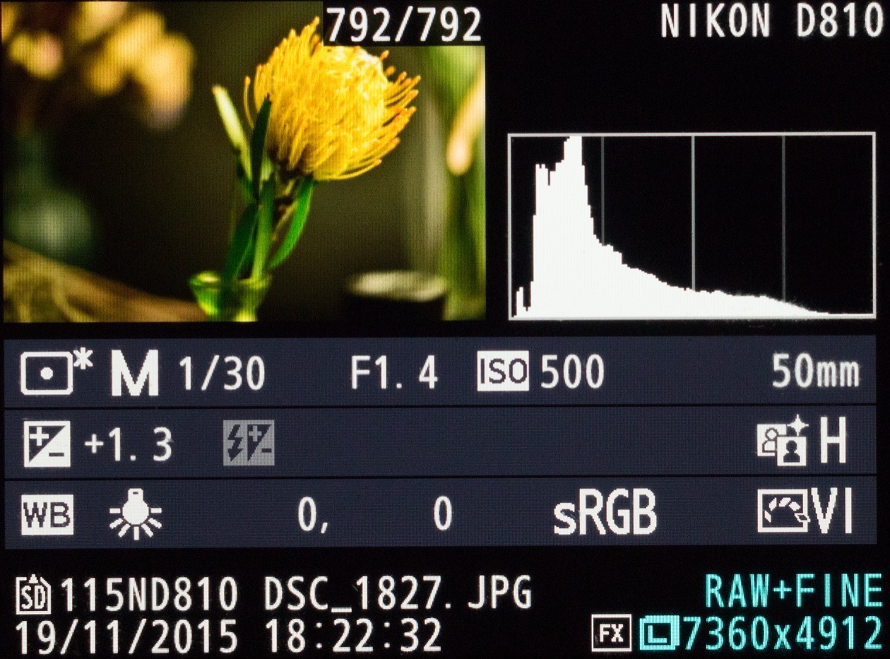 Camera playback screen showing a yellow flower photo, its luminance histogram and the shooting data