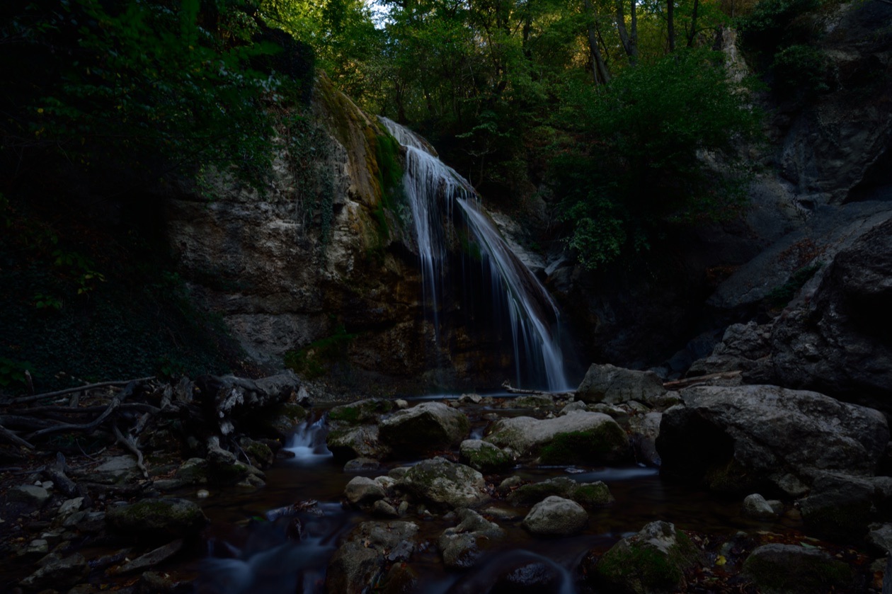 Underexposed photo of a waterfall in a rocky gorge, mostly dark