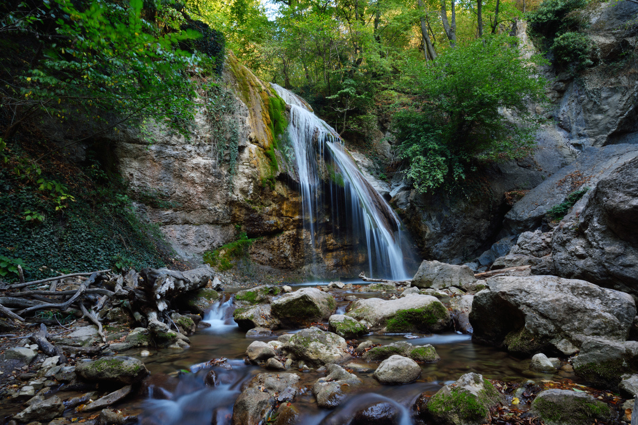 The same waterfall photo brightened in a RAW converter, with detail in the rocks and trees