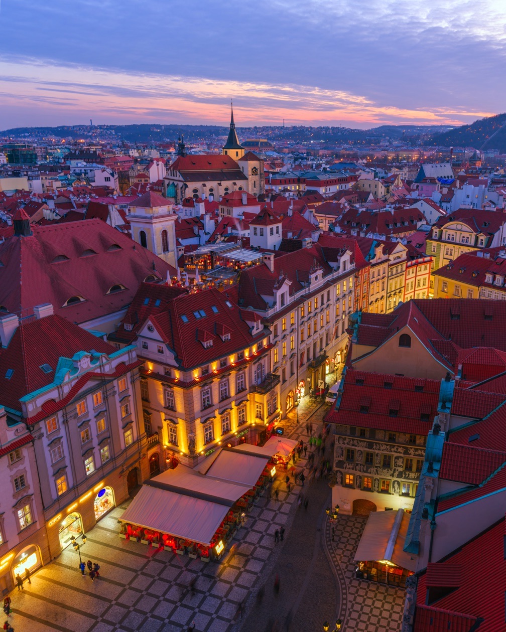 Old town square with red roofs and lit streets seen from above at twilight