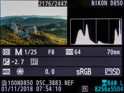 Camera playback screen of a mountain landscape whose histogram has a peak stuck to the right edge