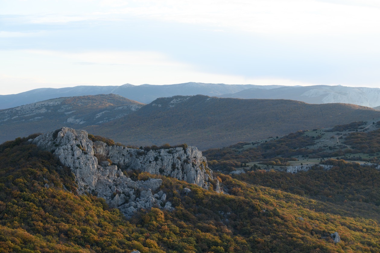 Mountain landscape with a rocky ridge and a bright, partly washed-out sky