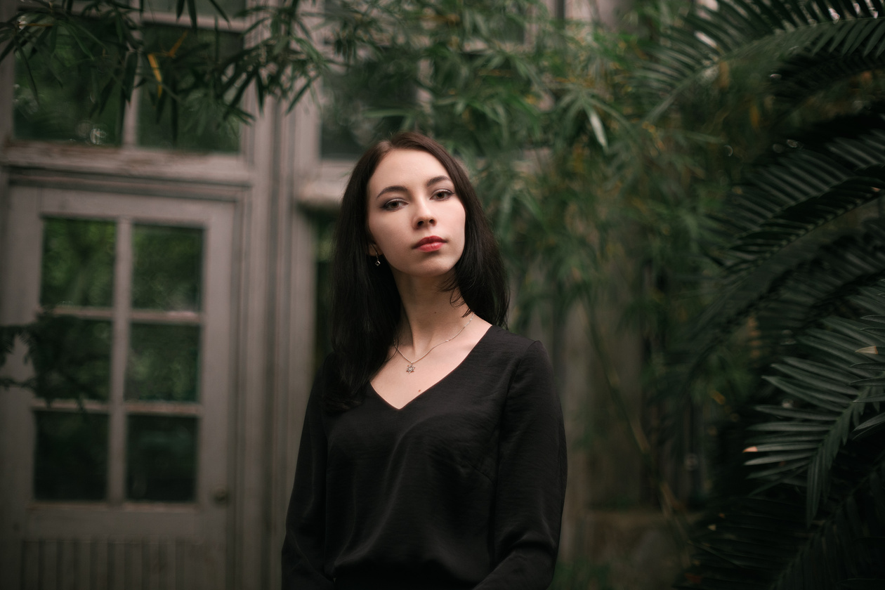 Portrait of a young woman in a black top among tropical plants, with soft rendering