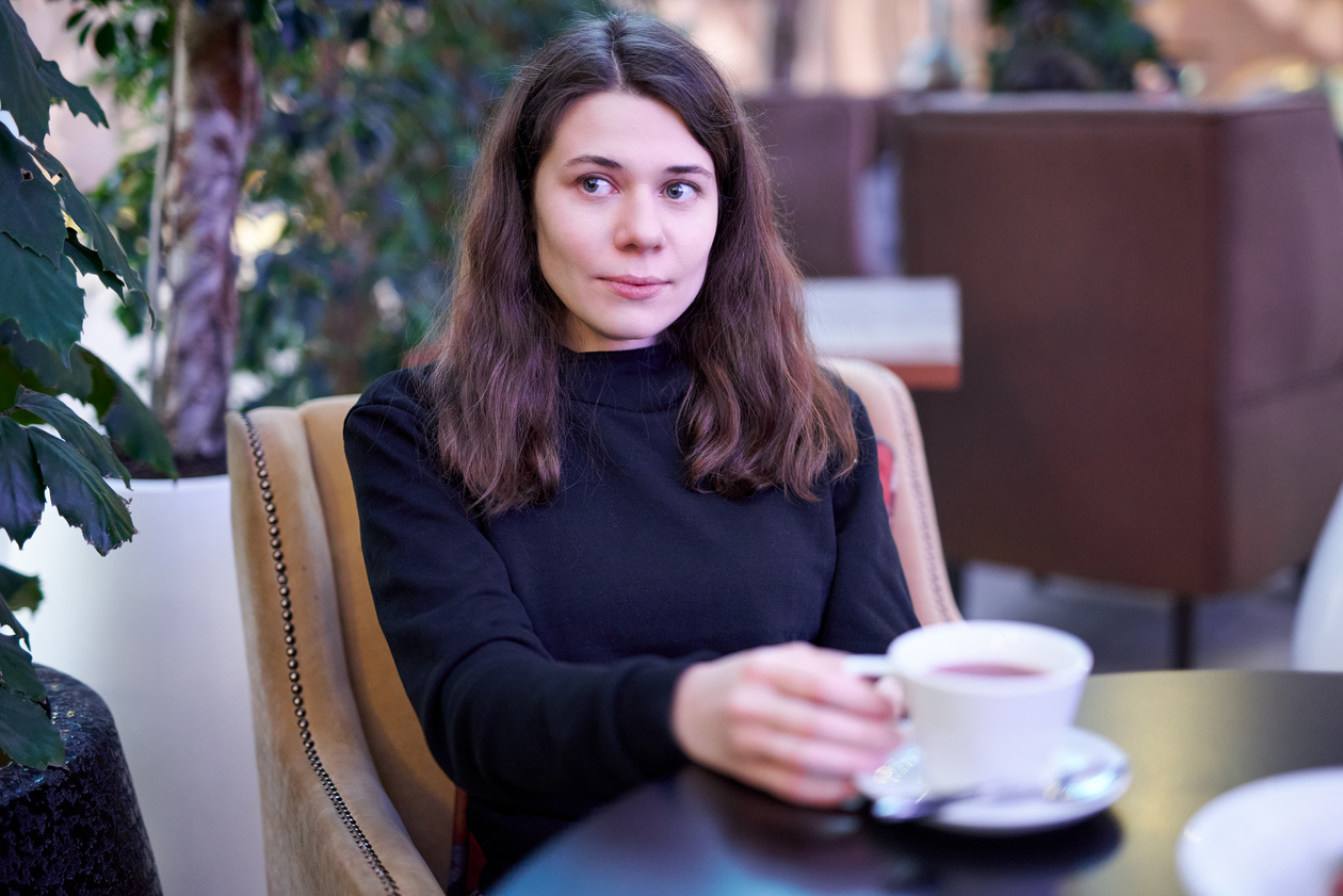 Young woman with a cup of tea at a café table, looking to the side