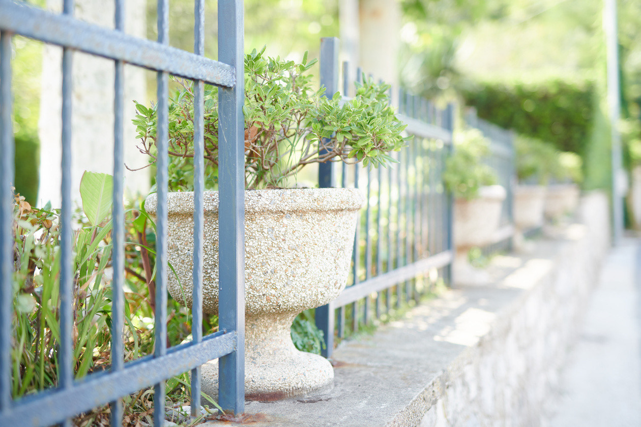 Stone flower urn behind an iron fence, shot wide open with a softly blurred background