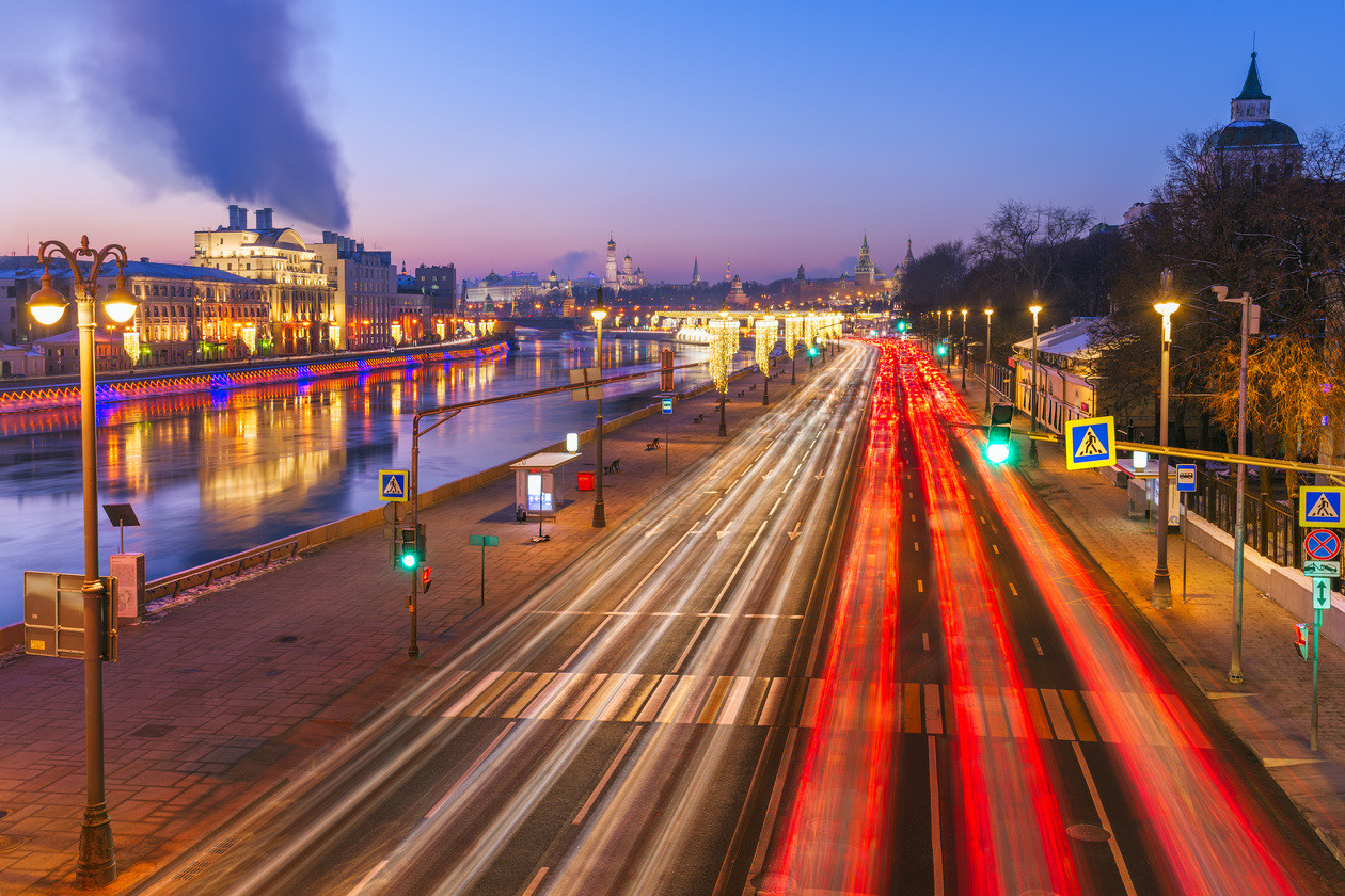 City embankment at dusk with red and white light trails from moving traffic