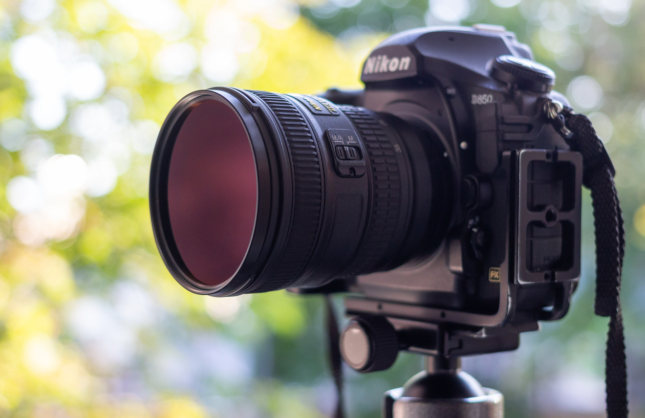 Nikon camera on a tripod with a round screw-in ND filter on the lens