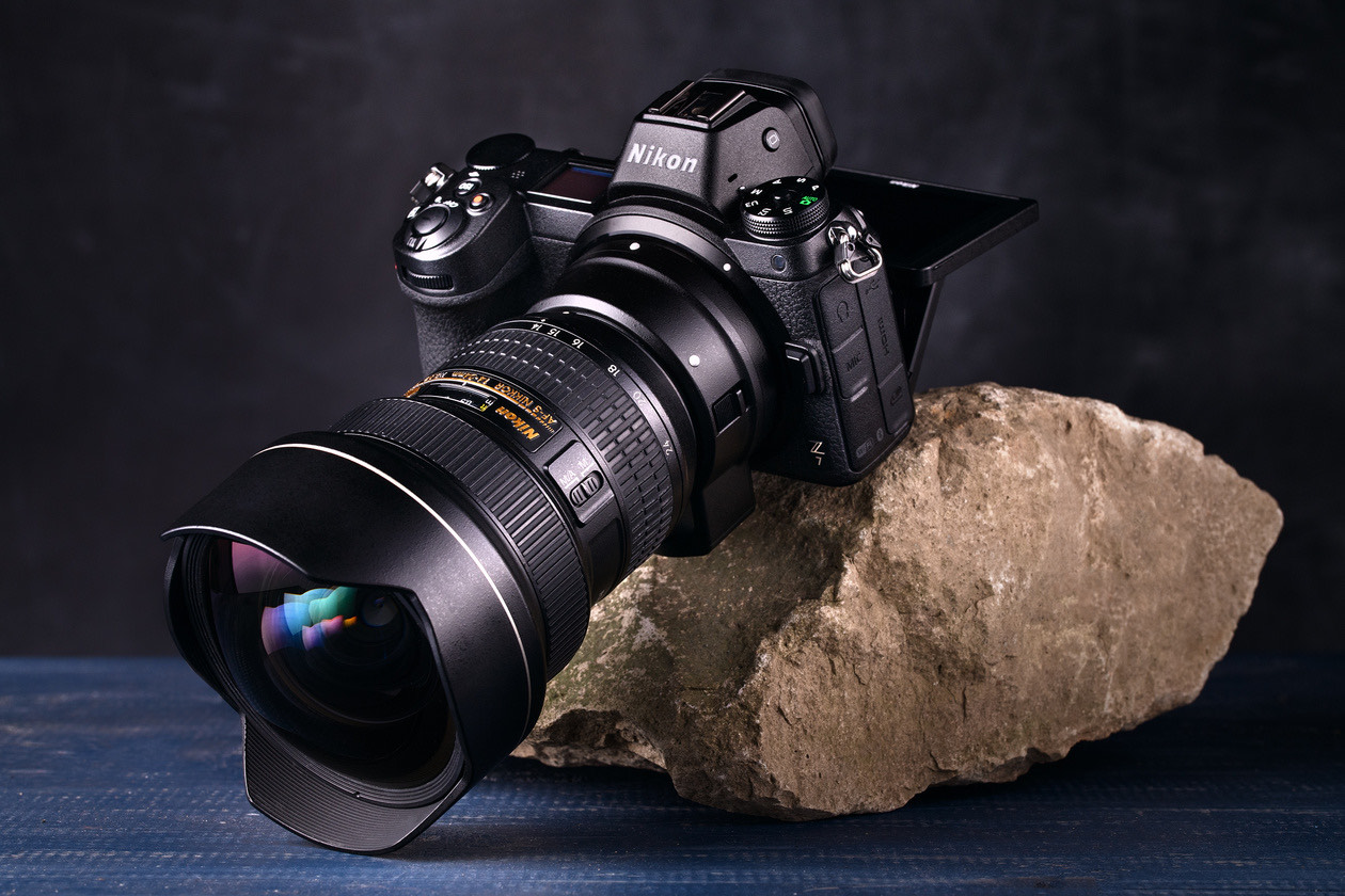 Nikon mirrorless camera with an ultra-wide zoom lens with a bulging front element, resting on a rock