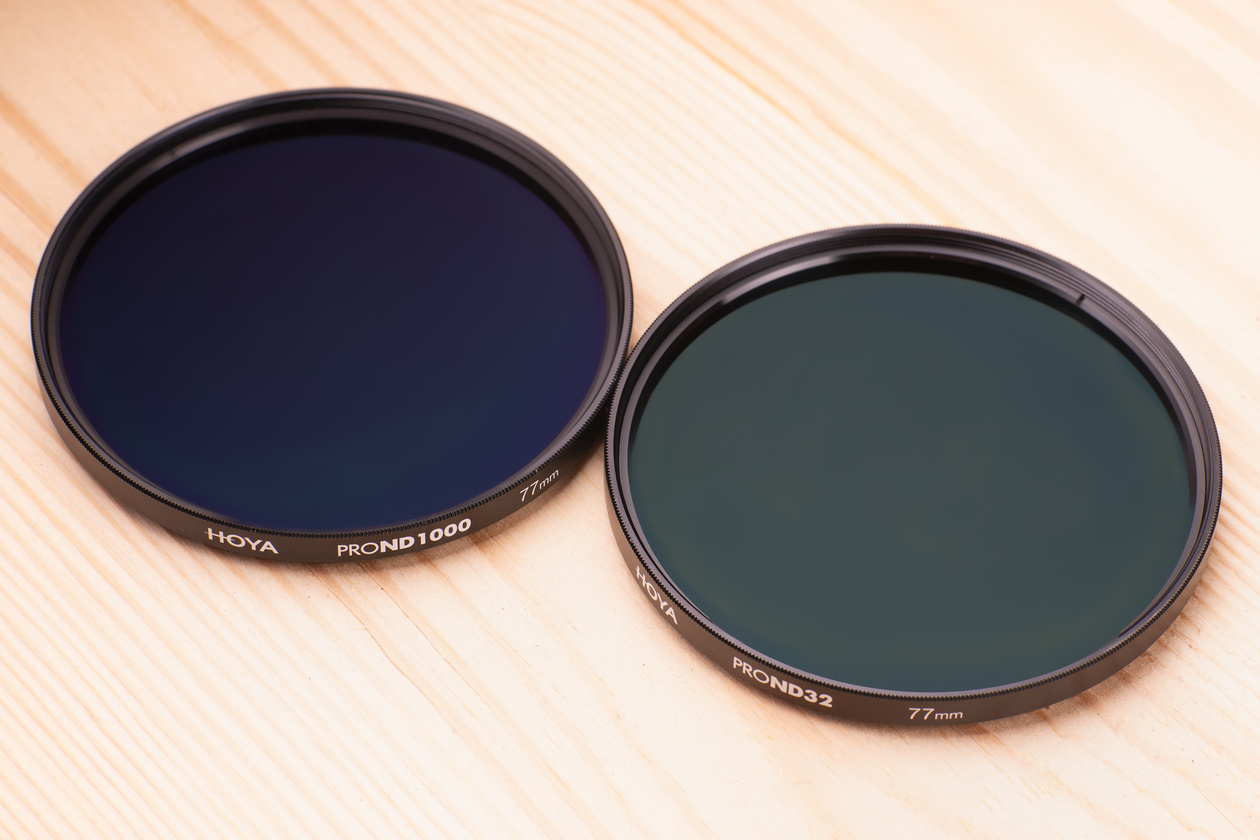 Two round screw-in Hoya ND filters, a ProND1000 and a ProND32, on a wooden surface