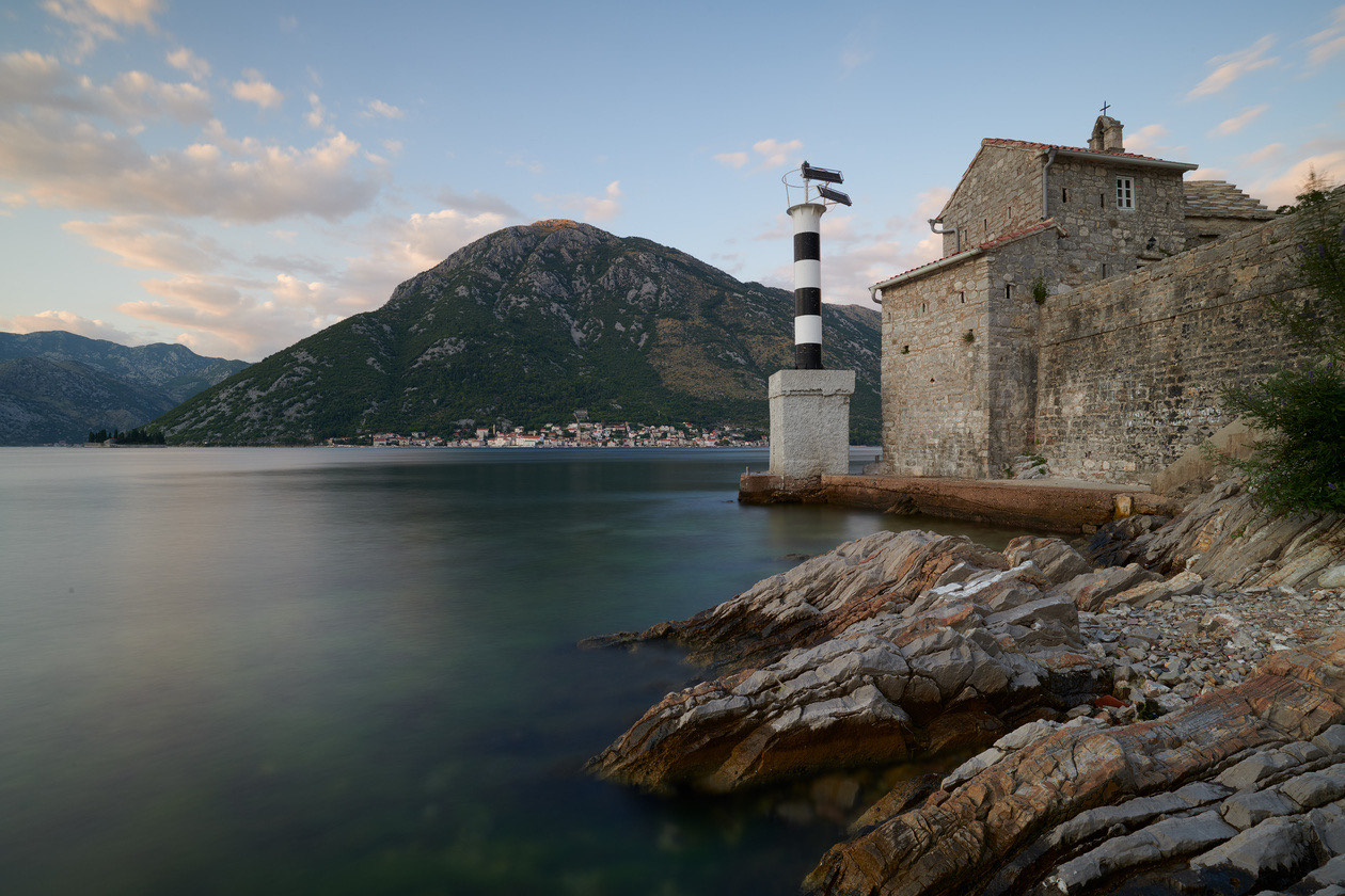 The same lighthouse and stone building on the bay with smoother water from a longer exposure