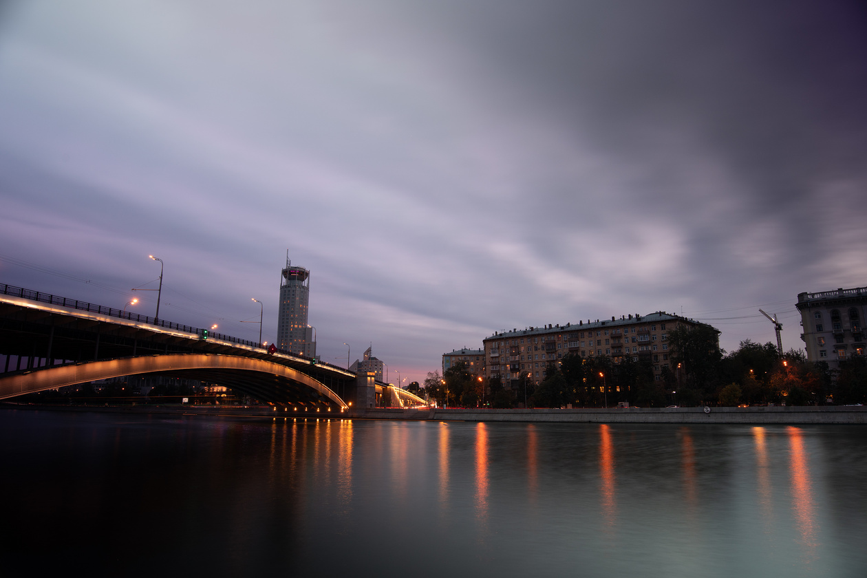 Bridge and city lights over a river at dusk with a long-exposure sky