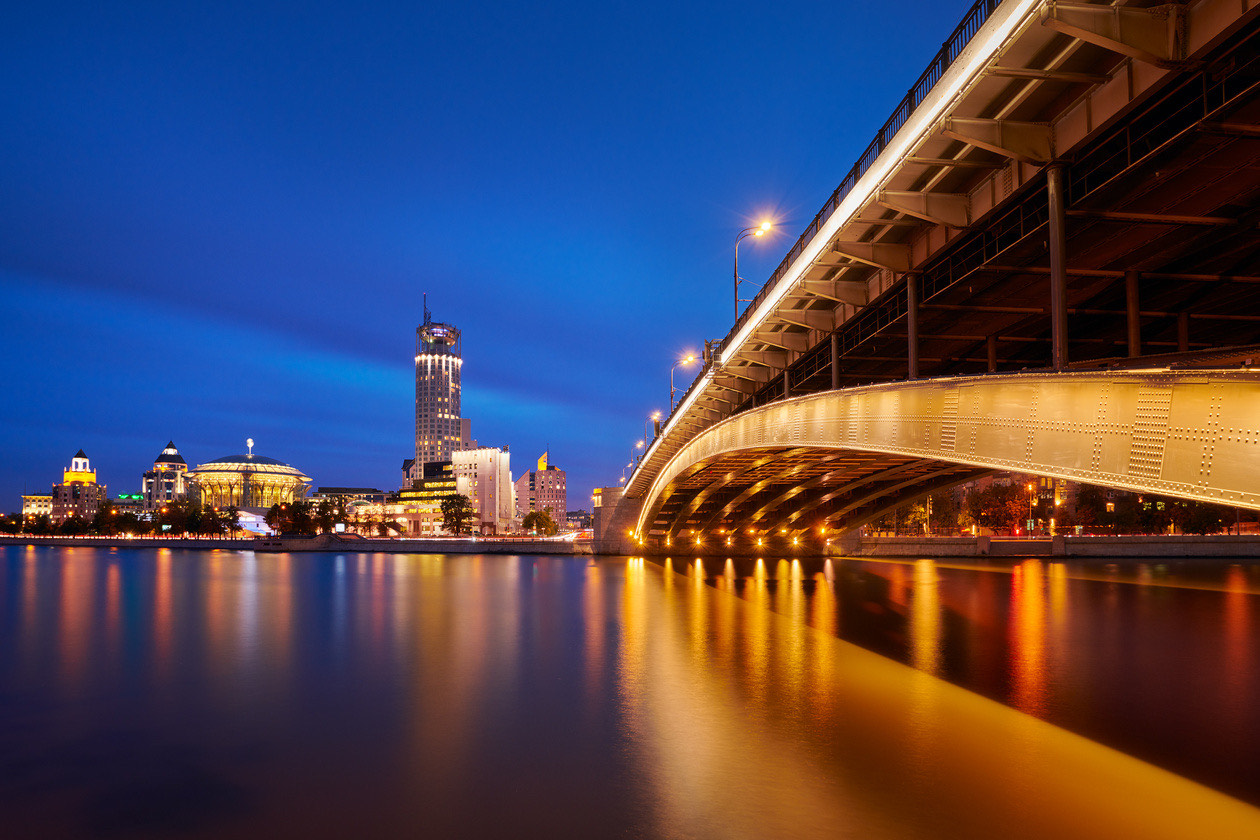 Illuminated bridge and city skyline reflected in a river at blue hour