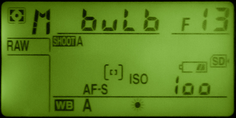 Camera top LCD panel in manual mode showing bulb at F13 and ISO 100