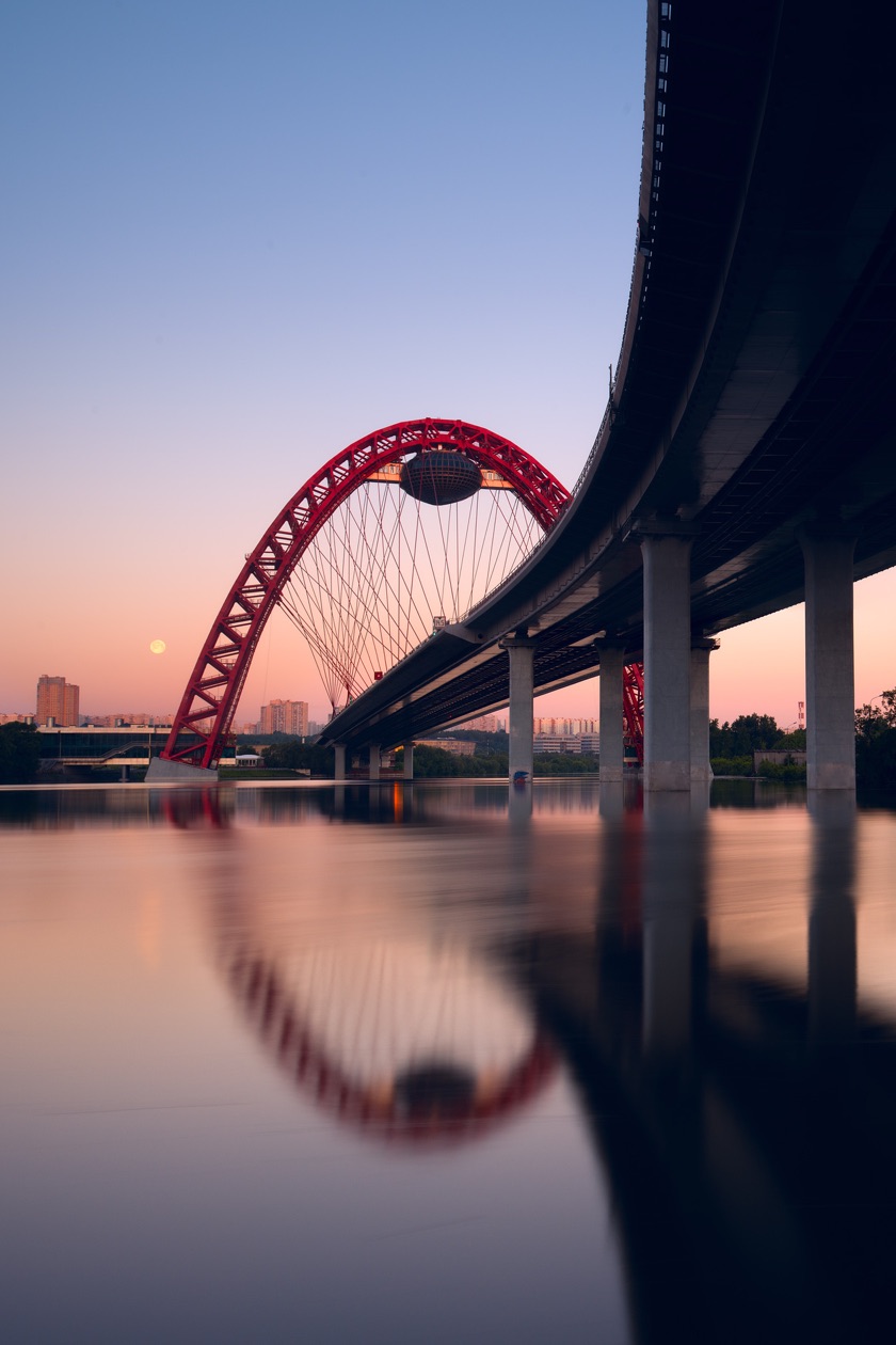 Red arched bridge reflected in still water at dusk, shot at a long exposure