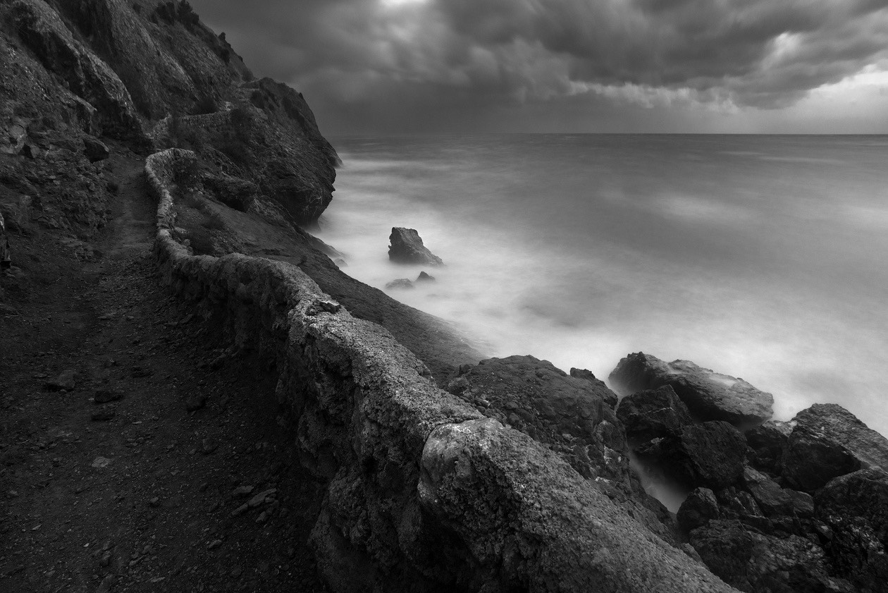 Black and white seascape of a rocky coast with misty long-exposure water