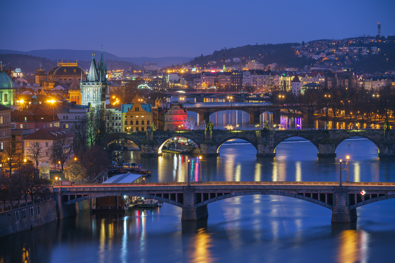 Old town with arched bridges over a river lit up at blue hour