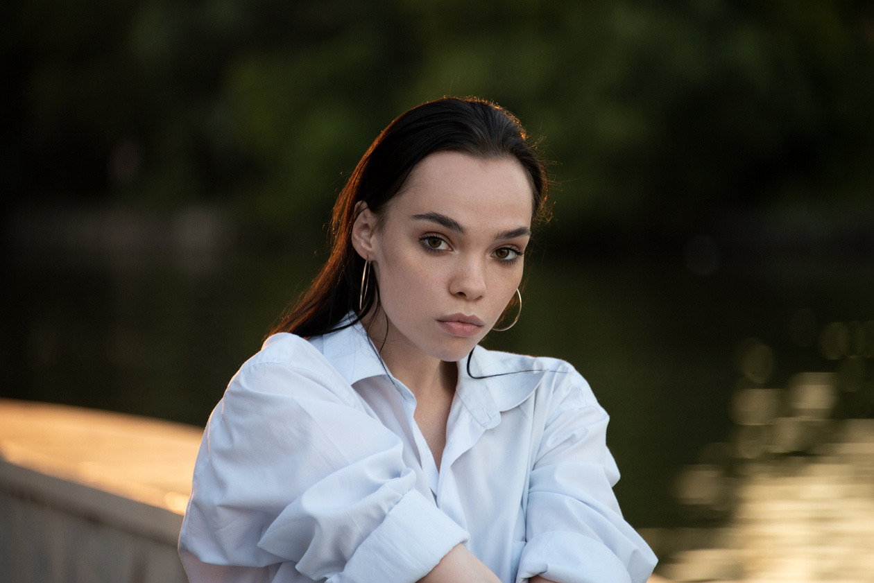 Young woman in a white shirt by a river in soft evening light