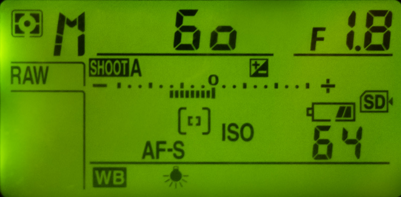 Green-lit top LCD of a DSLR showing 60 for the shutter speed and F1.8